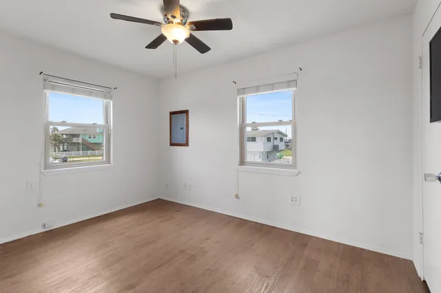 an empty room with windows and fan