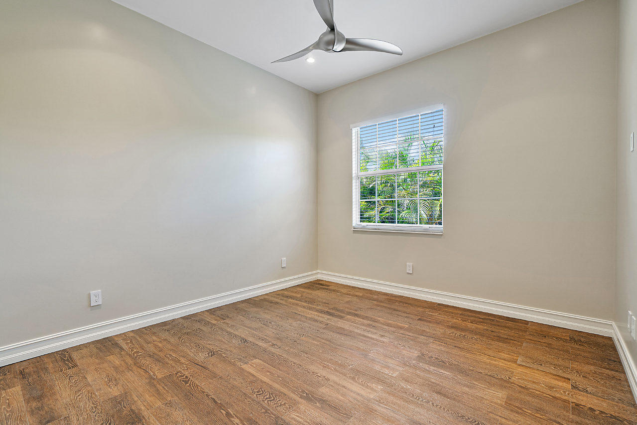3605 Gulfstream Road Palm Springs, FL 33461 - Photo 23 of 35 an empty room with wooden floor ceiling fan and windows