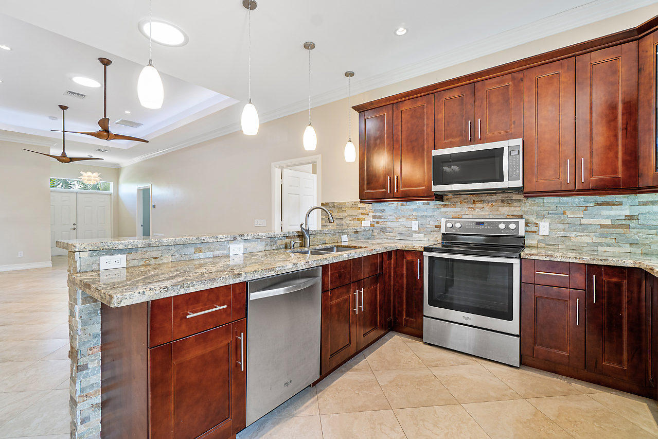 3605 Gulfstream Road Palm Springs, FL 33461 - Photo 5 of 35 a kitchen with stainless steel appliances granite countertop wooden cabinets a stove and a sink
