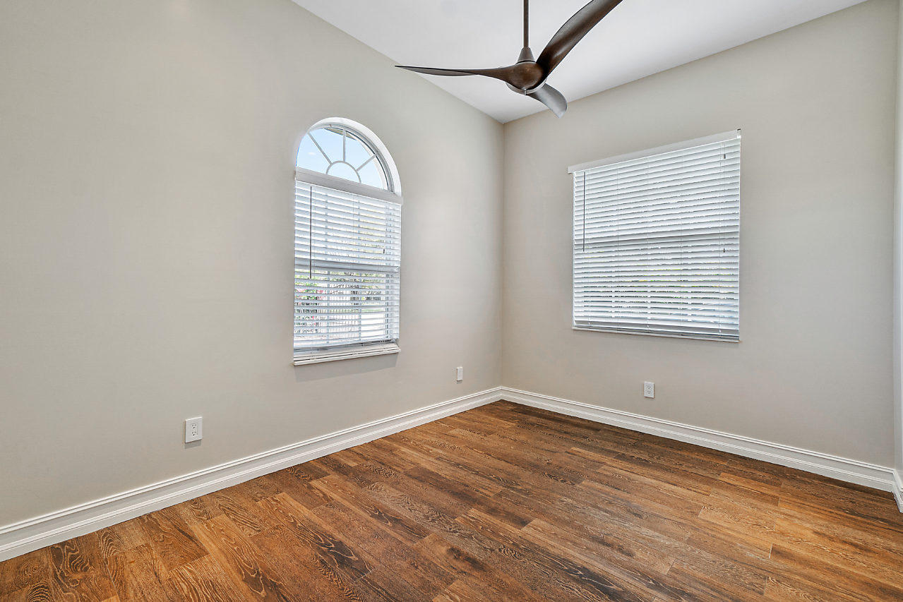 3605 Gulfstream Road Palm Springs, FL 33461 - Photo 7 of 35 an empty room with wooden floor chandelier fan and windows