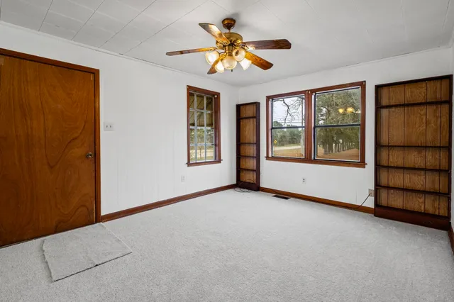 an empty room with windows and fan