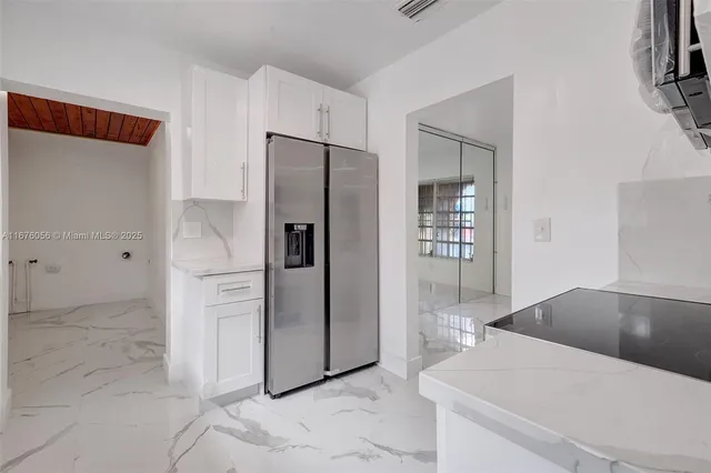an empty room with chandelier fan and windows