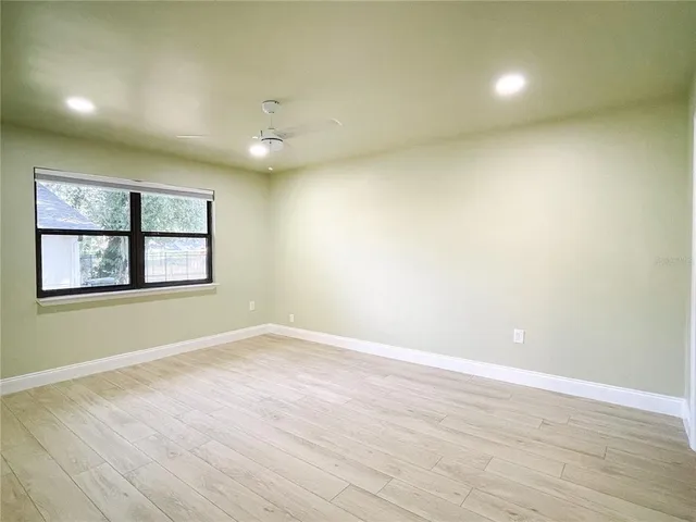 an empty room with wooden floor and windows