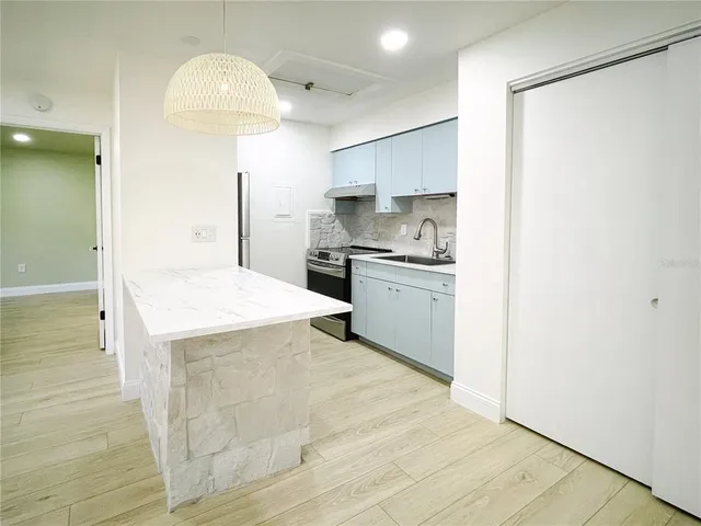 a large kitchen with stainless steel appliances a stove refrigerator and cabinets