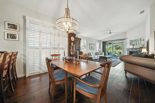 a kitchen with stainless steel appliances granite countertop a refrigerator a stove a sink dishwasher a dining table and chairs with wooden floor