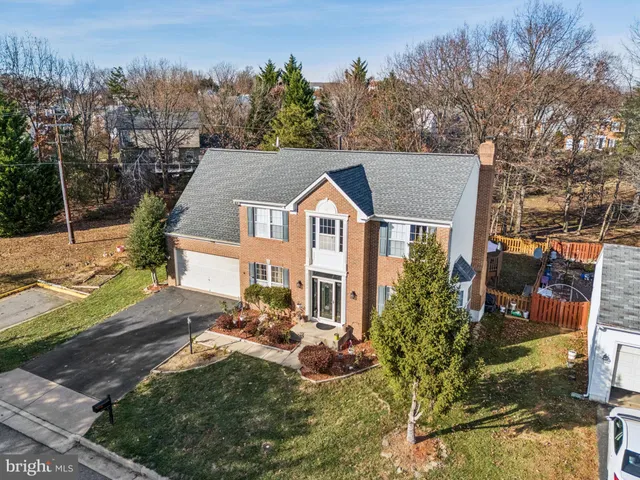 a aerial view of a house with yard and trees in the background