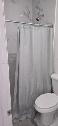 a white toilet sitting next to a shower curtain