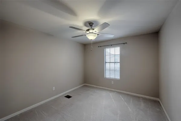 an empty room with windows and ceiling fan
