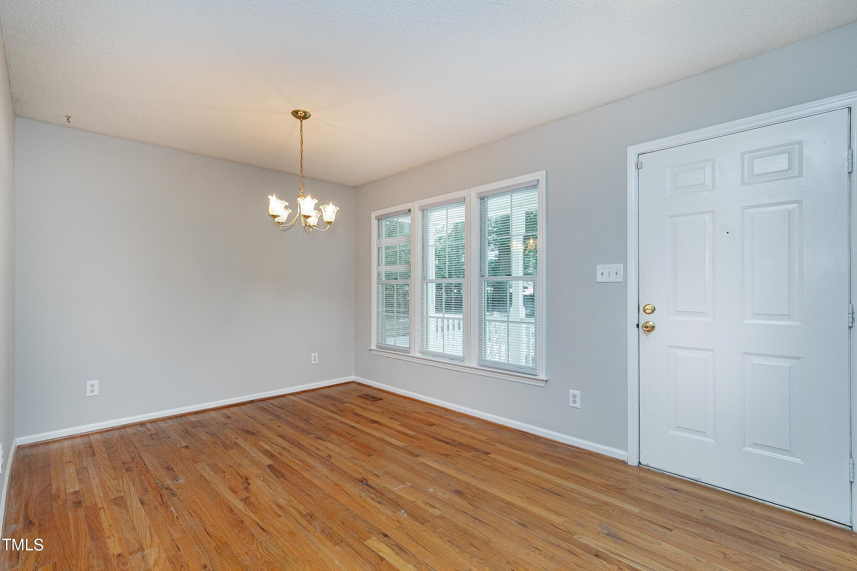 2313 Ruddy Road Raleigh, NC 27616 - Photo 9 of 32 an empty room with wooden floor chandelier and windows
