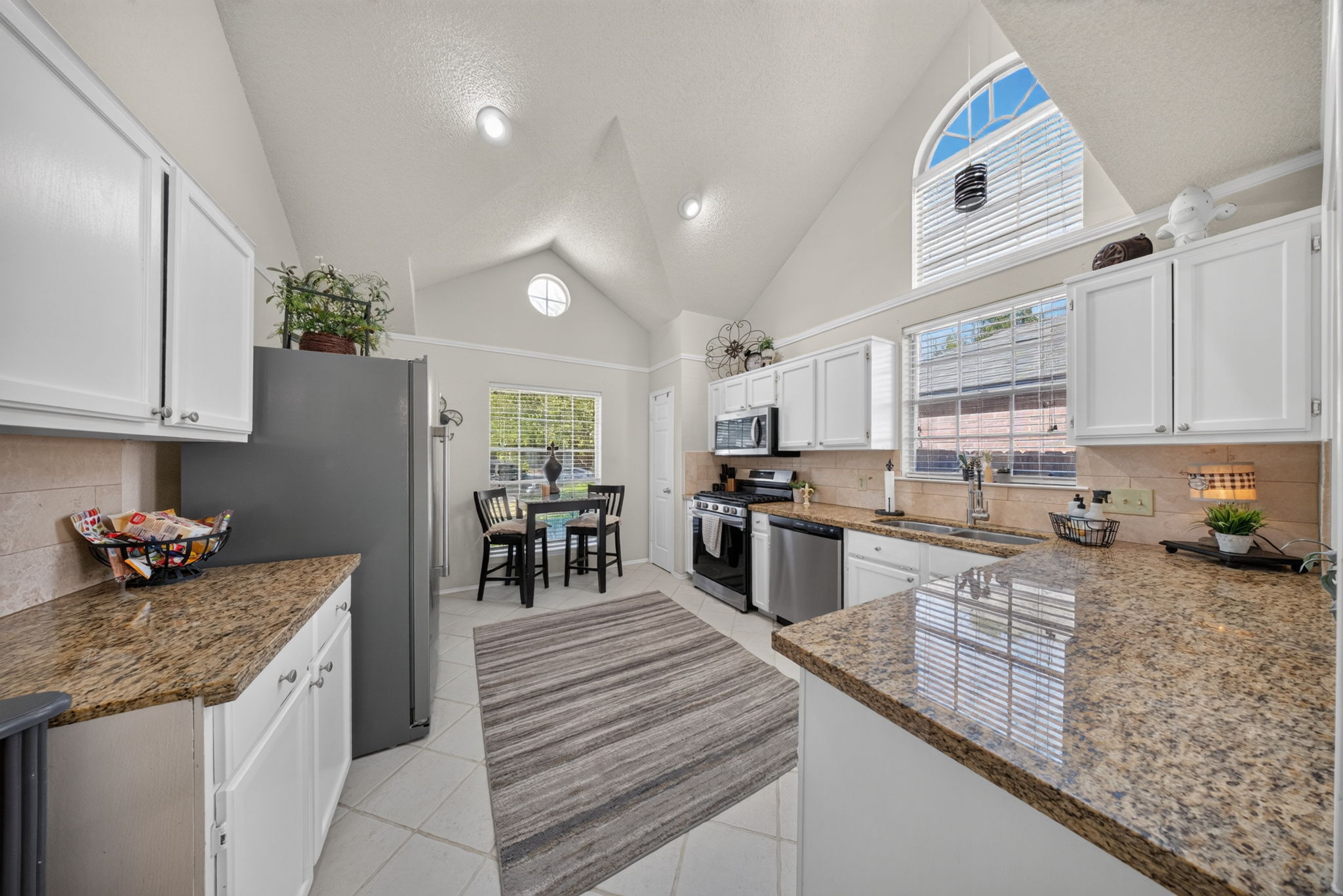 806 Mountain Ridge Drive Leander, TX 78641 - Photo 16 of 40 Dramatic vaulted ceilings and durable tile flooring define this bright, eat-in kitchen space.