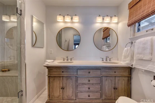 a bathroom with a toilet a double vanity sink and a mirror