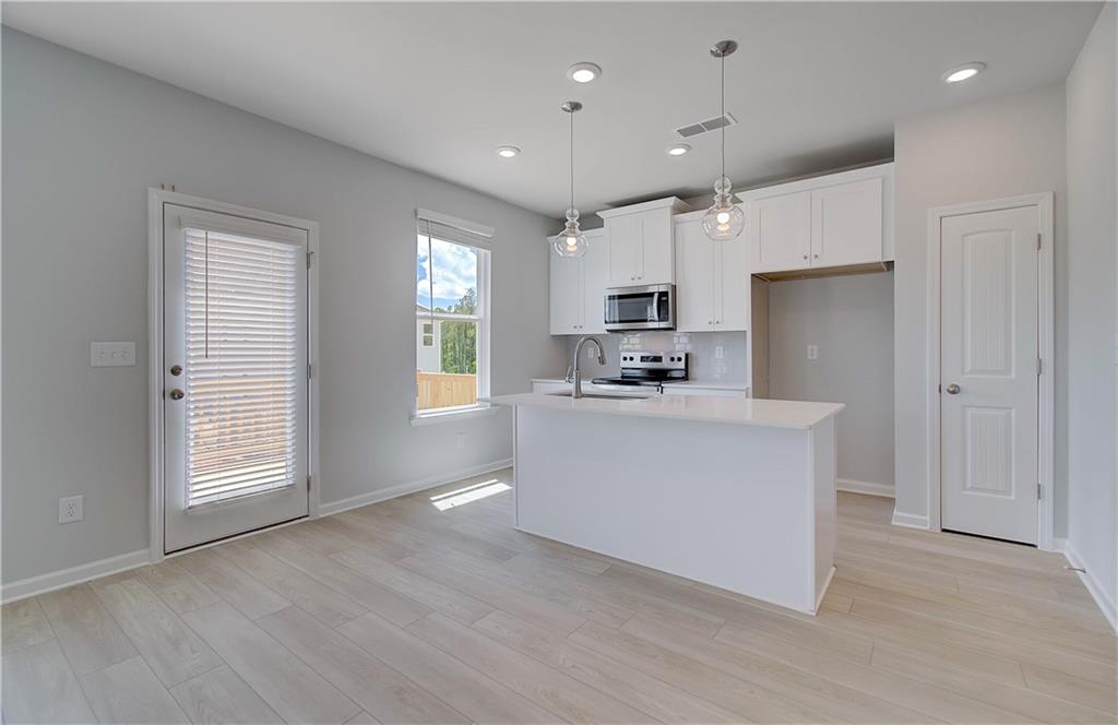 107 Alpine Road Fairburn, GA 30213 - Photo 8 of 22 a kitchen with kitchen island a sink a center island stainless steel appliances and a window