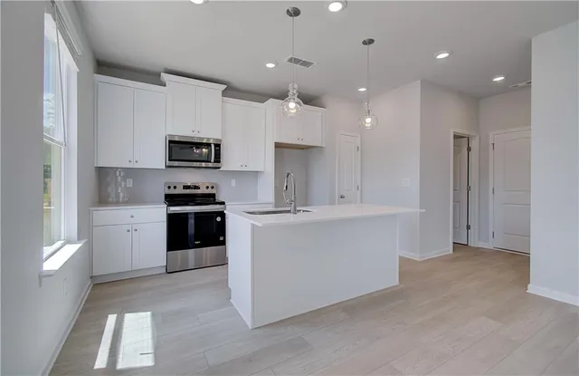 a kitchen with kitchen island a sink stainless steel appliances and cabinets