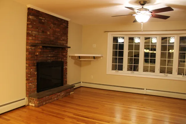 a view of an empty room with a window and wooden floor