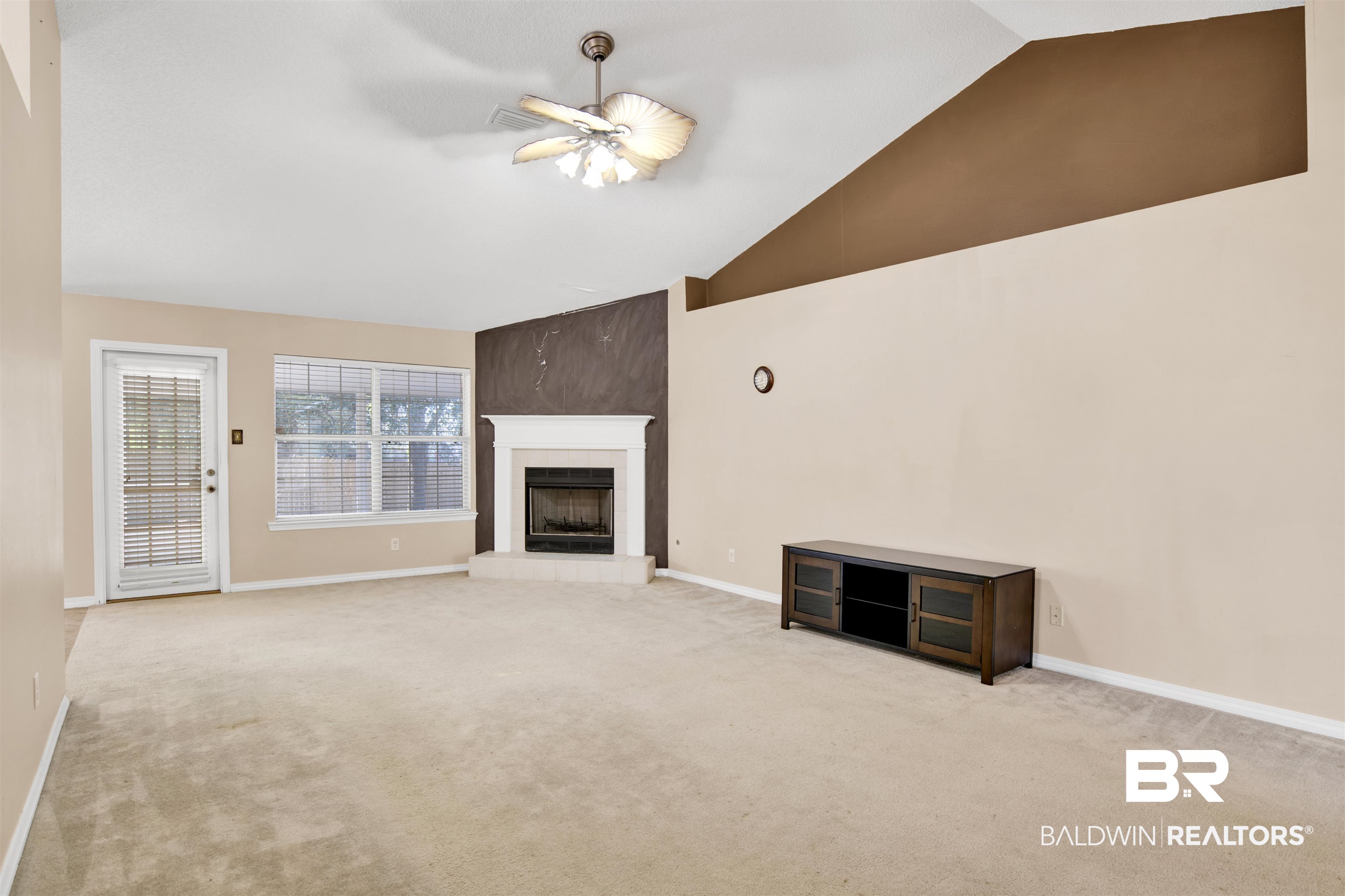 7297 Bridgemill Drive Mobile, AL 36619 - Photo 8 of 33 Unfurnished living room featuring lofted ceiling, a fireplace with raised hearth, carpet flooring, and a ceiling fan