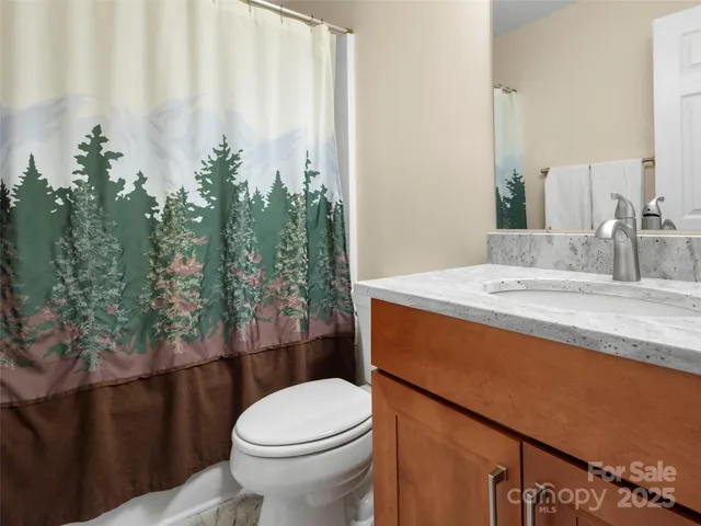 a bathroom with a granite countertop sink and a toilet