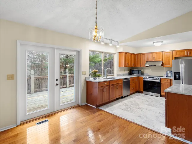 a kitchen with stainless steel appliances granite countertop a stove top oven a sink dishwasher a dining table and chairs with wooden floor