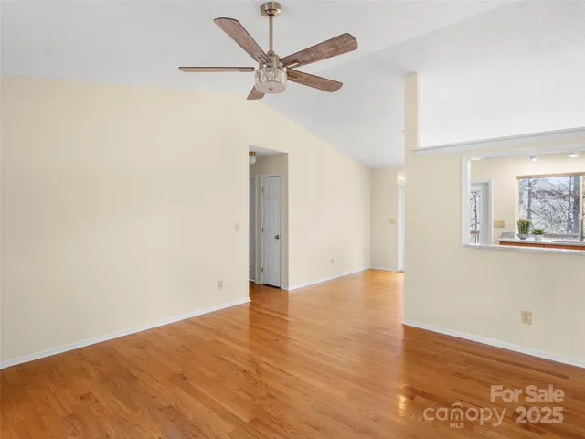 an empty room with wooden floor fan and windows