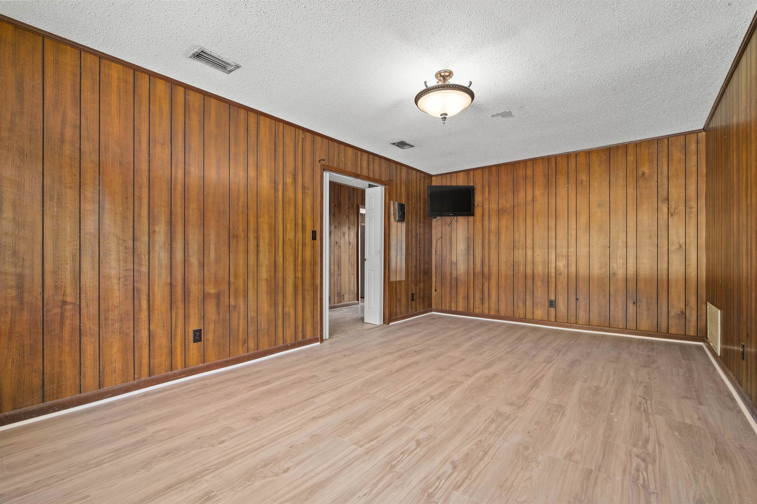 10285 Argyle Road Irvington, AL 36544 - Photo 13 of 28 Unfurnished room with wooden walls, light wood-style floors, and a textured ceiling