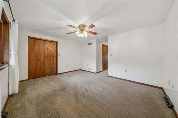 an empty room with chandelier fan and windows