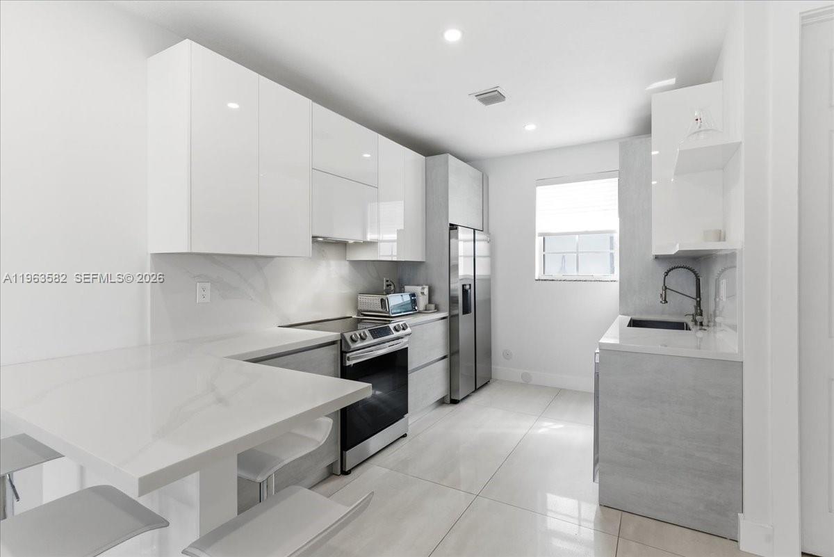 7743 Southwest 99th Street, Unit 2 Miami, FL 33156 - Photo 2 of 40 a kitchen with a stove a sink and a refrigerator