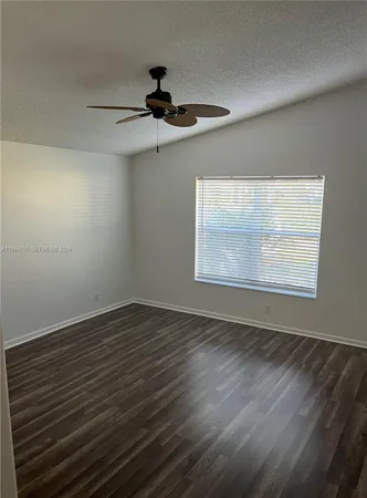 an empty room with wooden floor chandelier fan and windows