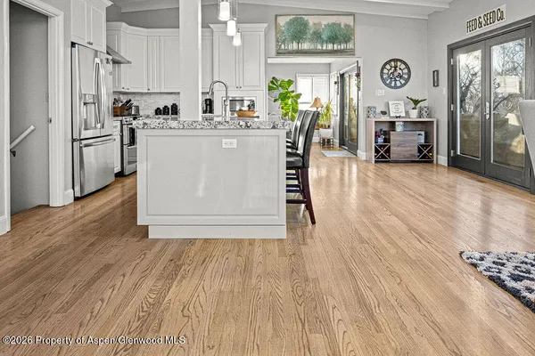 a living room with stainless steel appliances furniture a large window and a wooden floor