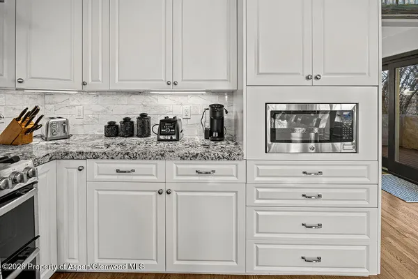 a kitchen with granite countertop white cabinets and stainless steel appliances