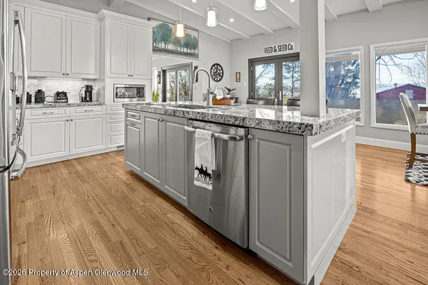 a kitchen with stainless steel appliances granite countertop a sink cabinets and wooden floor