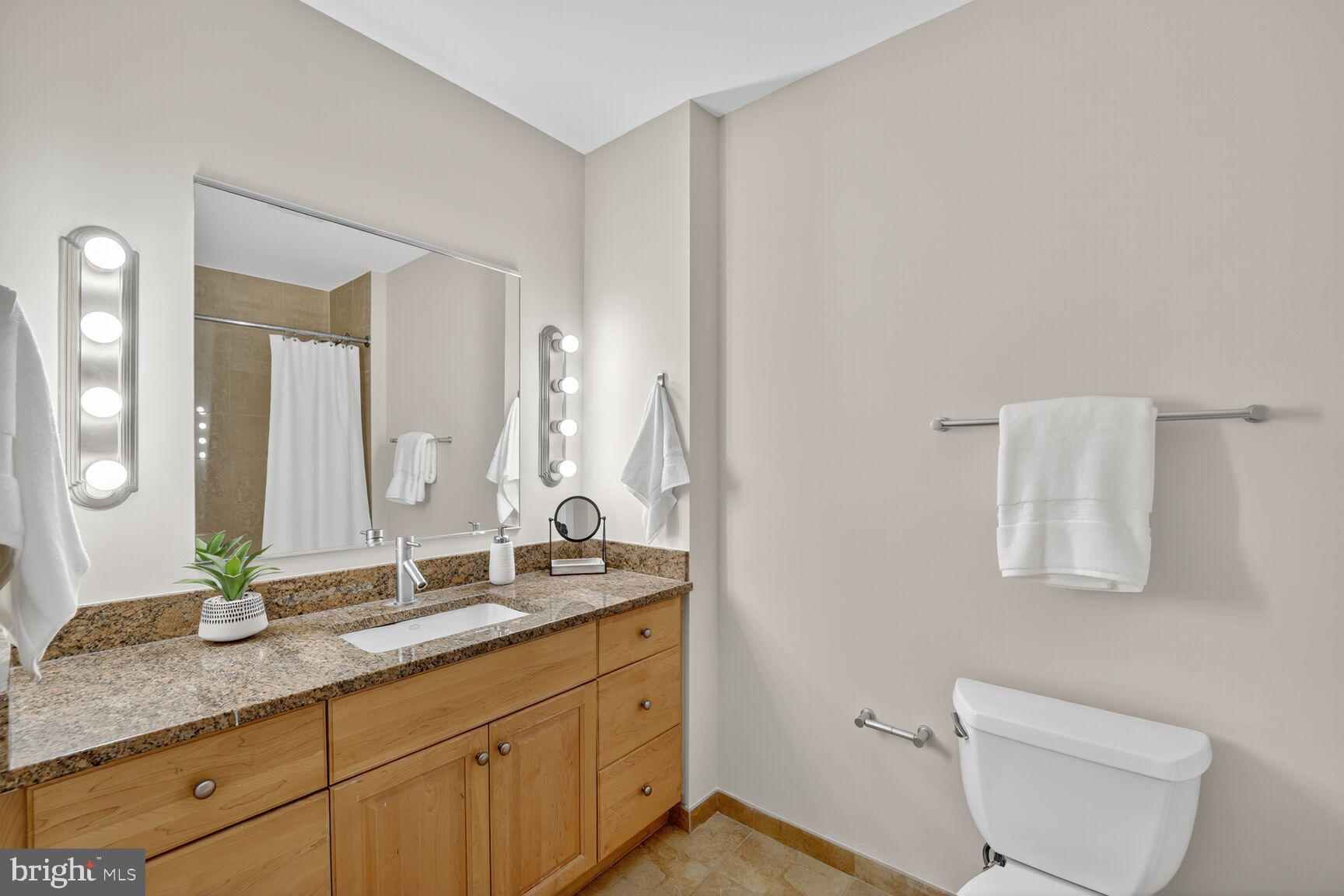811 4th Street Northwest, Unit 807 Washington, DC 20001 - Photo 15 of 32 a bathroom with a granite countertop sink a toilet and a mirror