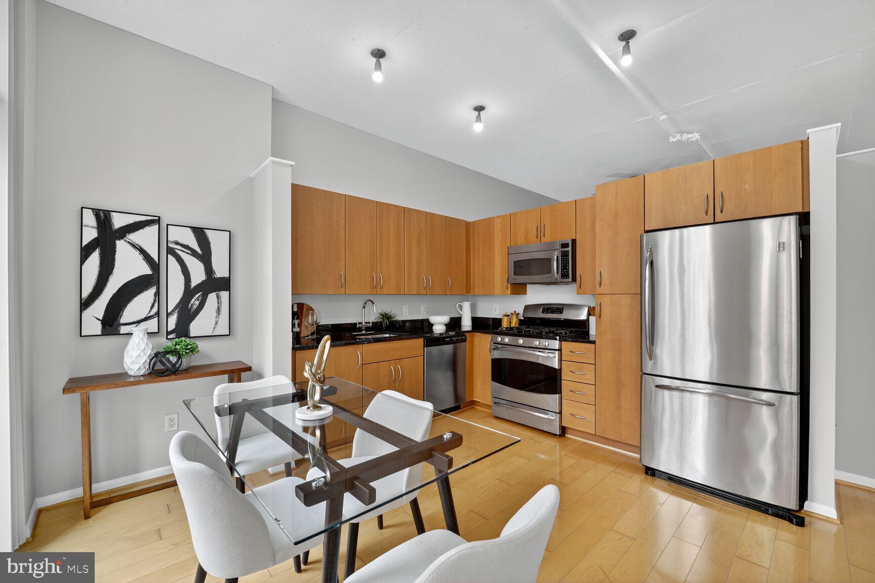 811 4th Street Northwest, Unit 807 Washington, DC 20001 - Photo 5 of 32 a kitchen with stainless steel appliances granite countertop a refrigerator a stove a sink a dining table and chairs with wooden floor