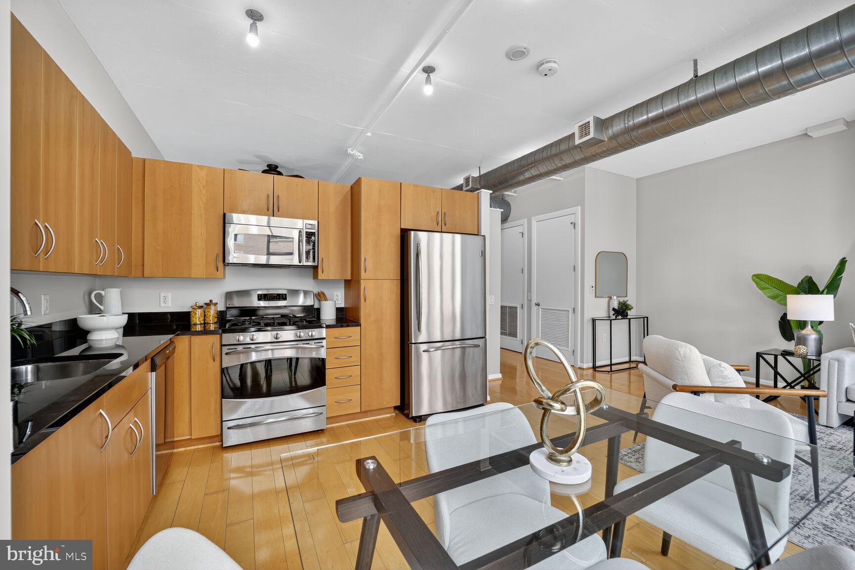 811 4th Street Northwest, Unit 807 Washington, DC 20001 - Photo 7 of 32 a kitchen with stainless steel appliances granite countertop a refrigerator a stove top oven a sink dishwasher and dining table with wooden floor
