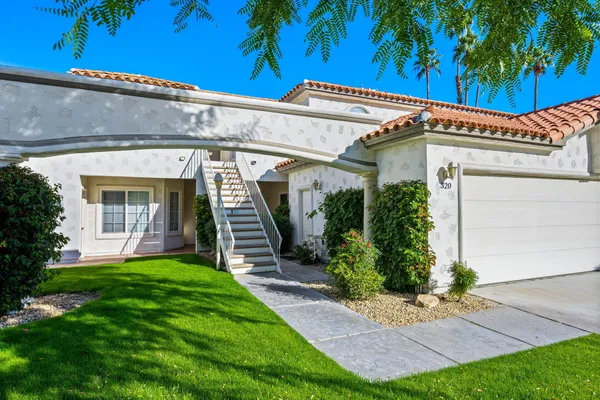 a view of a house with a yard and potted plants