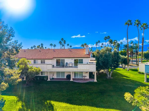 a view of a house with a big yard potted plants and large tree