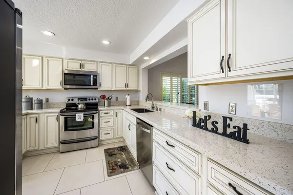 a kitchen with granite countertop a sink a stove top oven and cabinetry