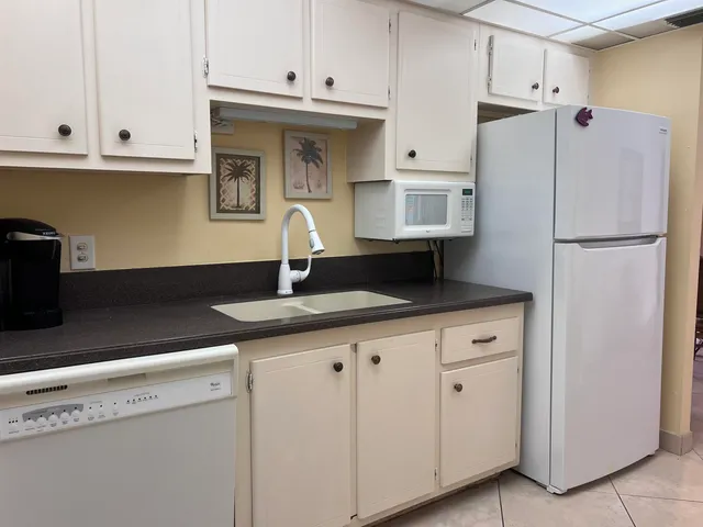 a kitchen with granite countertop white cabinets and refrigerator