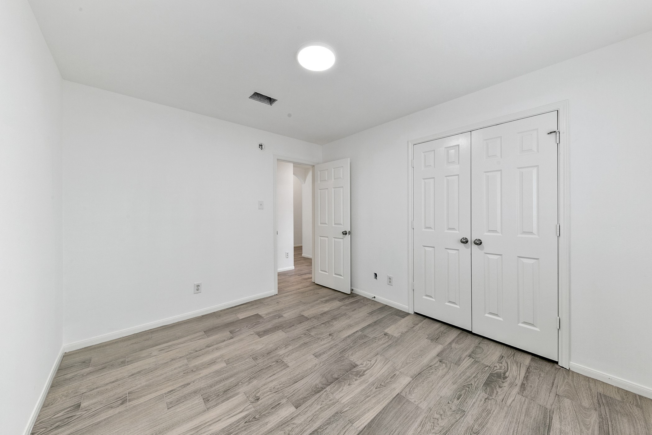 12014 Raven View Drive Houston, TX 77067 - Photo 11 of 29 This room features a clean, minimalist design with white walls and light wood flooring. It includes a ceiling light, a closet with double doors, and an entry door, creating a bright and functional space.