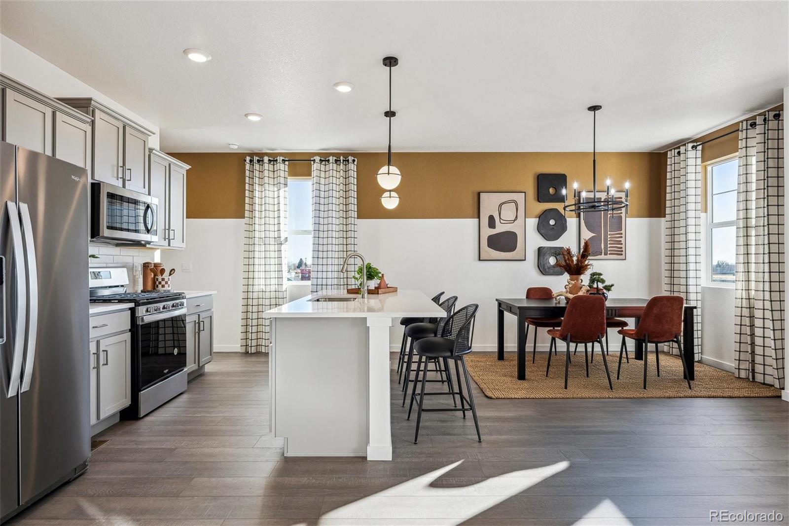 932 Logan Peak Way Berthoud, CO 80513 - Photo 11 of 34 a kitchen with kitchen island granite countertop a stove a refrigerator a dining table and chairs with wooden floor