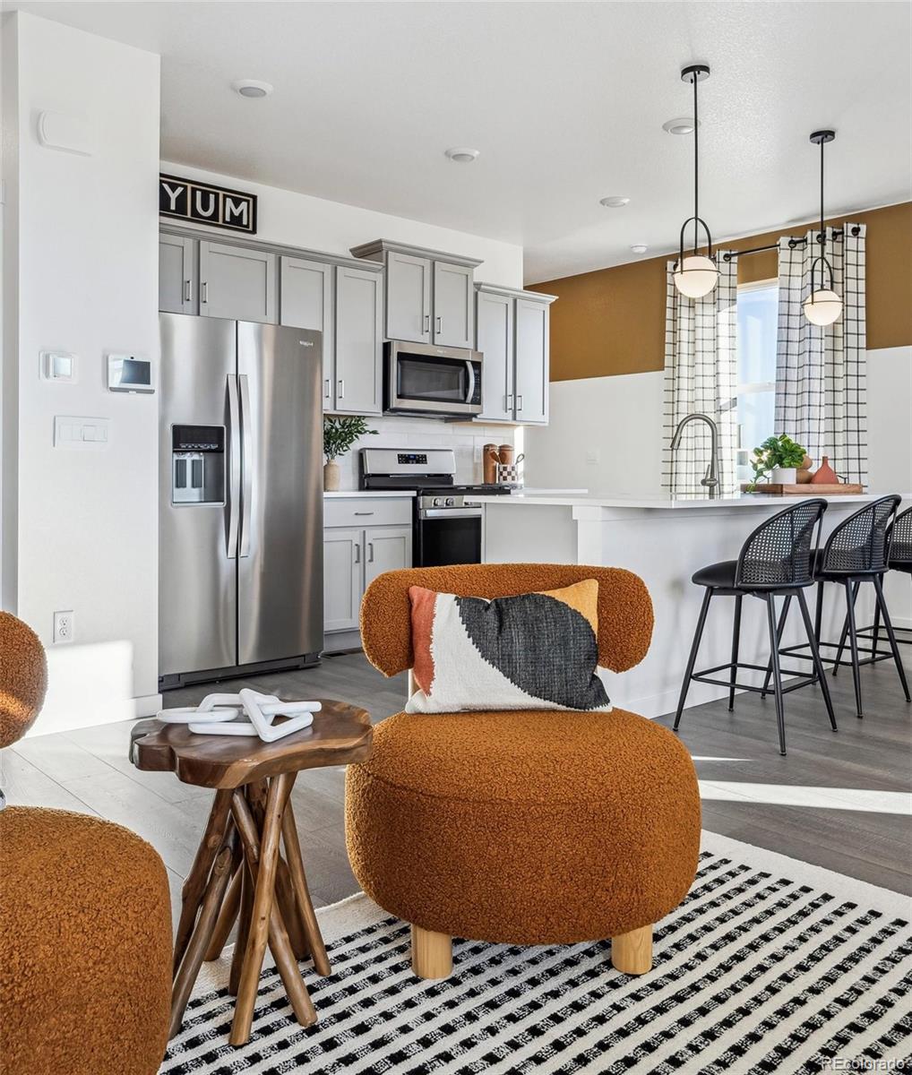 932 Logan Peak Way Berthoud, CO 80513 - Photo 8 of 34 a kitchen with stainless steel appliances kitchen island granite countertop a refrigerator a stove a sink dishwasher with a dining table and chairs