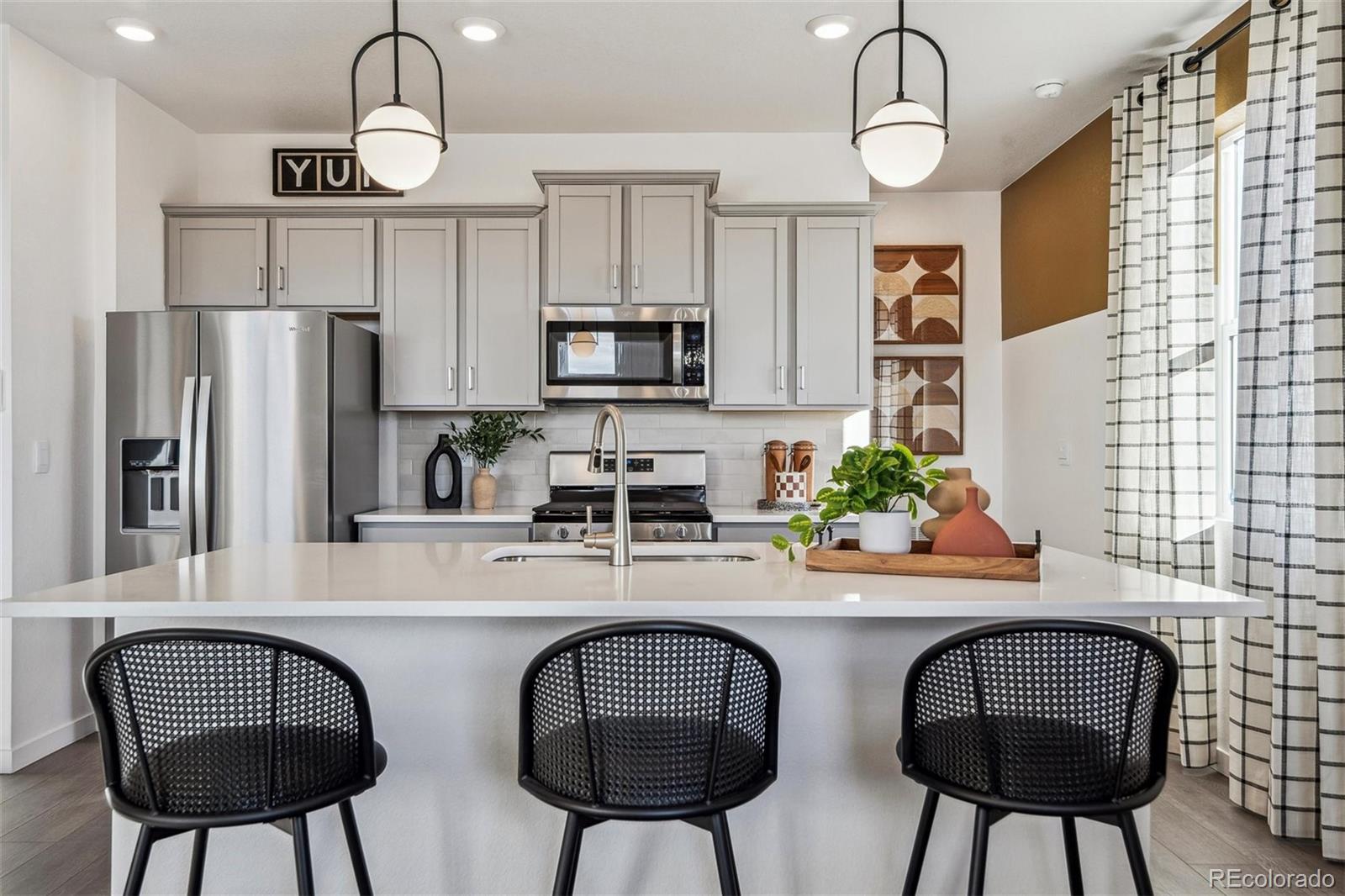 932 Logan Peak Way Berthoud, CO 80513 - Photo 10 of 34 a kitchen with stainless steel appliances a dining table chairs a microwave a refrigerator and cabinets