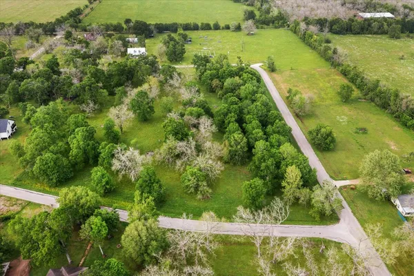 an aerial view of residential houses with outdoor space and trees all around
