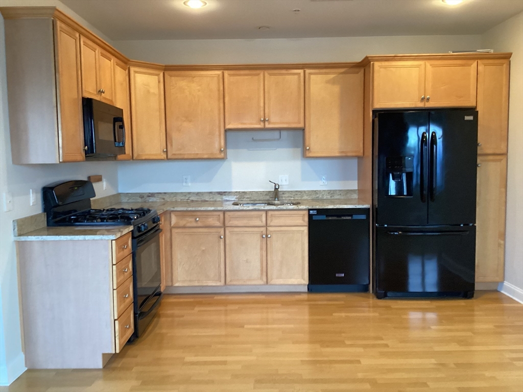 a kitchen with granite countertop a refrigerator and a stove top oven