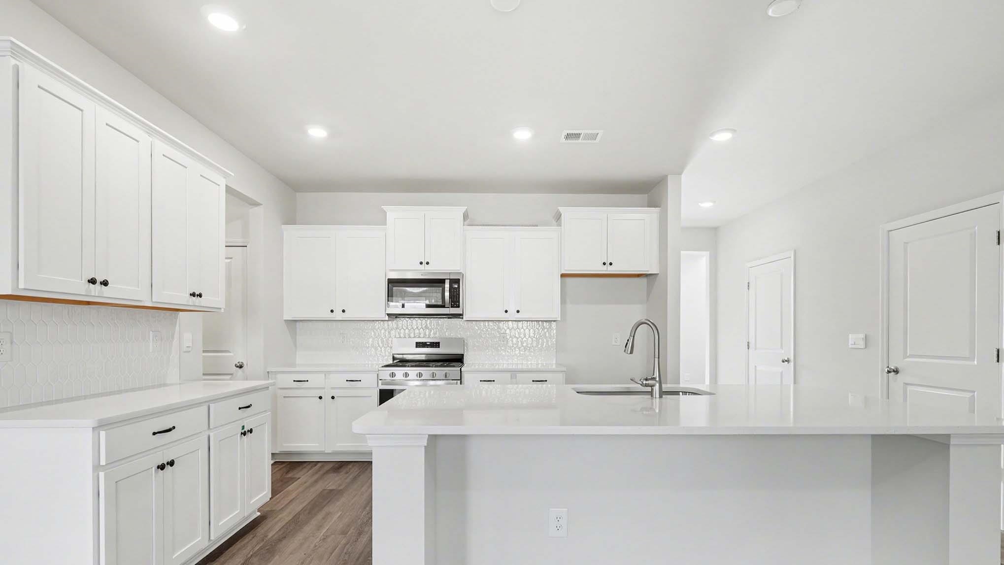 184 Bjorn Way Loris, SC 29569 - Photo 12 of 32 Kitchen with white cabinets, a center island with sink, gas stove, stainless steel microwave, and recessed lighting
