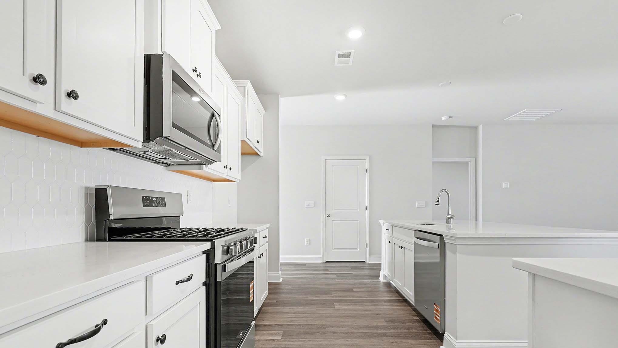 184 Bjorn Way Loris, SC 29569 - Photo 13 of 32 Kitchen with appliances with stainless steel finishes, white cabinetry, an island with sink, dark wood-style floors, and light stone countertops