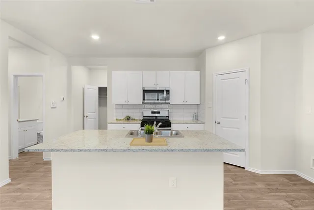 a kitchen with stainless steel appliances granite countertop a sink refrigerator and cabinets