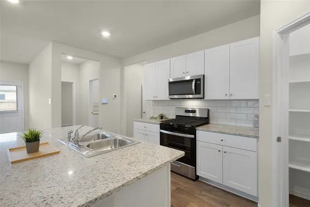 a kitchen with stainless steel appliances granite countertop a sink a stove and a granite counter tops