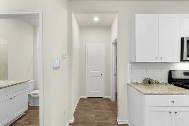 a view of hallway with granite countertop white cabinets and white appliances