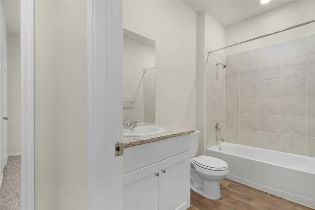 a bathroom with a granite countertop bathtub shower sink vanity and toilet