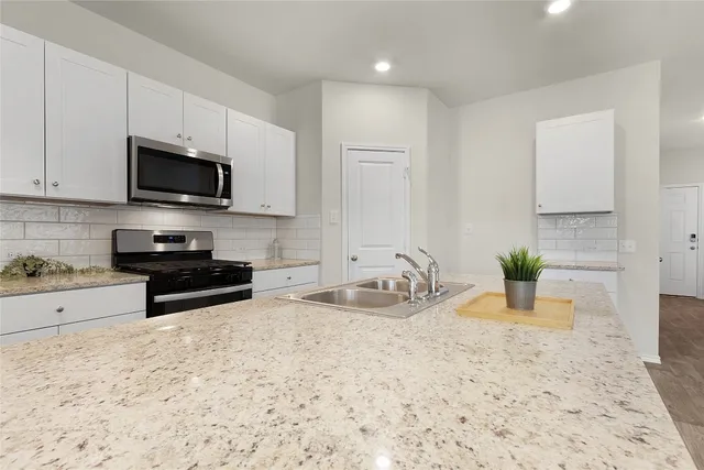 a kitchen with sink a stove and cabinets