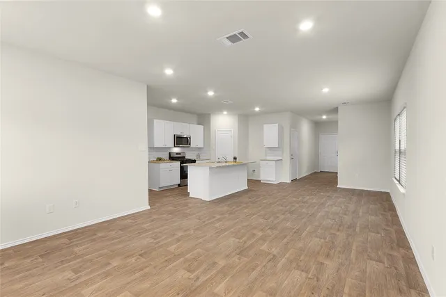 a view of kitchen with kitchen island a sink wooden floor and a refrigerator
